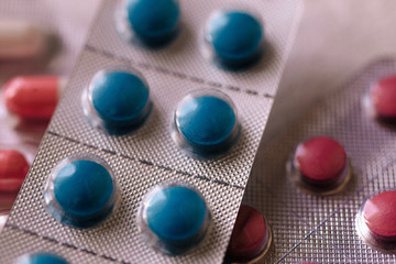 blisters of tablets of different colors - red, pink, green, blue pills and capsules