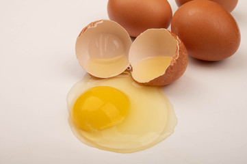 A broken chicken egg and scattered eggs on a white background. Close up.