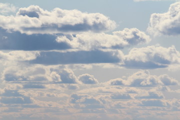 Clouds in the blue sky at sunset or dawn backlit by the sun. Place for text and design.