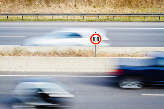 Speed Limit Sign Amidst Blur Cars On Street