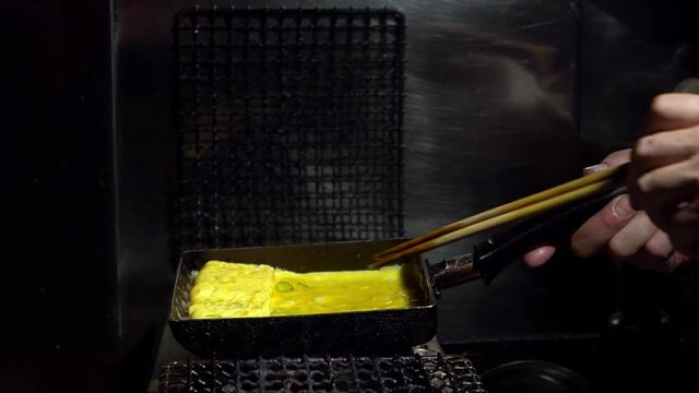Tamagoyaki omelettes in metal pans at a street food market in downtown Tokyo. Popular Japanese street food in the izakaya restaurant.-Dan