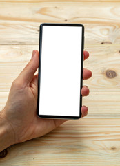 Man holding a smart phone with blank screen, wooden background