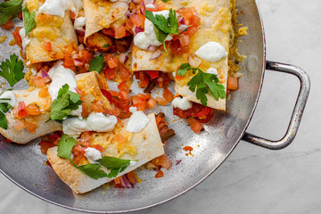 Mexican enchiladas topped with cheese, yoghurt sauce and coriander garnish. Vegetarian enchiladas made with lentils and red peppers. Mexican fast food. 