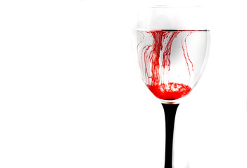 Glass with water and red paint on a white background