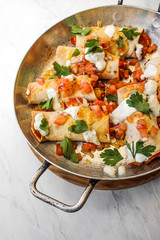 Mexican enchiladas topped with cheese, yoghurt sauce and coriander garnish. Vegetarian enchiladas made with lentils and red peppers. Mexican fast food. 