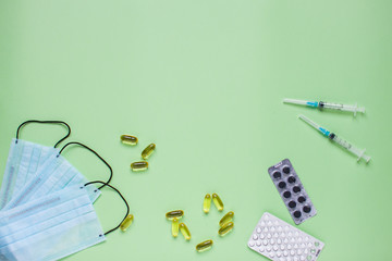 Surgical medical face masks, rubber protective gloves, syringes and pills. Coronavirus, protection concept. Global pandemic. Medicine. Layout. Green background