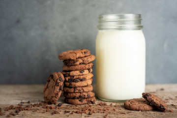 Close up of a few stacks of cookies and a glass of fresh milk.