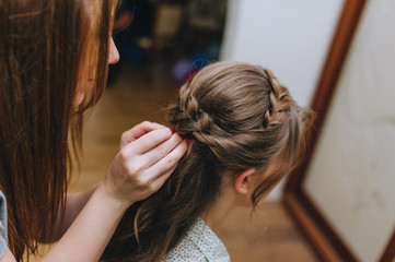 Naklejka premium Girl professional hairdresser braids the pigtail to the bride and makes a hairstyle close-up. Photography, concept.