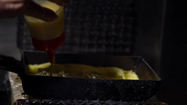 Slow Motion of tamagoyaki omelettes in metal pans at a street food market in downtown Tokyo. Popular Japanese street food in the izakaya restaurant.-Dan