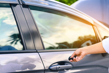 A focus image of a businesswoman's hand pressing a close-up car key in the evening after work