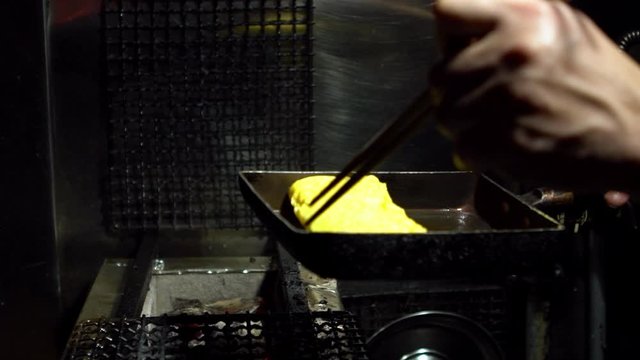 Slow Motion of tamagoyaki omelettes in metal pans at a street food market in downtown Tokyo. Popular Japanese street food in the izakaya restaurant.-Dan