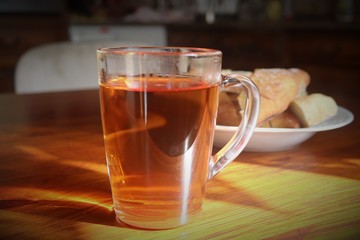 cup of tea and bread on a wooden table illuminated by the sun