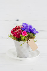 White vase with rose flowers and a tag for the inscription.