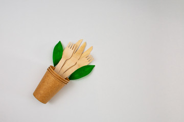 Zero waste concept. Forks and knives in a paper cup on a white background. Green leaflets.