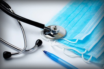 stethoscope, pen and medical protective masks on white background