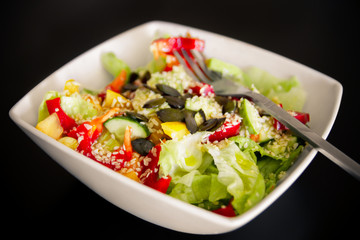 Vegetable Salad. Salad of tomato, cucumber, lettuce, sprinkled with sesame seeds. Salad in a white plate.