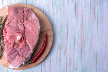 piece of pork meat on the bone, chilli on a round wooden cutting board