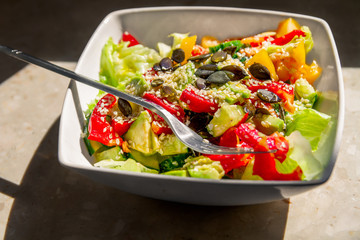 Vegetable Salad. Salad of tomato, cucumber, lettuce, sprinkled with sesame seeds. Salad in a white plate.