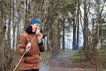 woman outdoors cooks by the fire