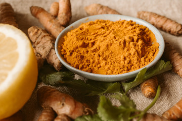 Turmeric roots and powder as background. Organic and healthy food. Close up view. 	