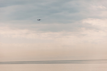 the plane in the sky over the sea on a summer day.