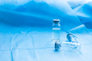 Glass medicine bottles with syringe injection and empty ones,dropper system on blue texture surgical sterile covering background. Coronavirus vaccine development of virus antidote.Copy space.Flat lay.