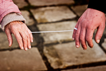 A young hand is tied with a thread to the old. Hands are tied together by a thread close up....