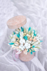 Composition of cozy flowers in a 
beige hat box. Floral bouquet of flowers of cotton flowers, gypsophila, wheat and lagurus for a gift for mothers day