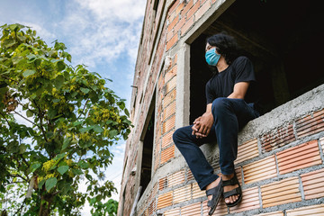 Asian man is wearing mask and sit on the step during covid19 or corona virus spread