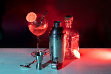 cocktail on table, with cocktail shaker, glass and bottle