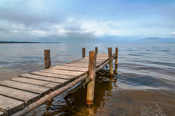 Perspective view of wooden pier at lake. Small bridge in water