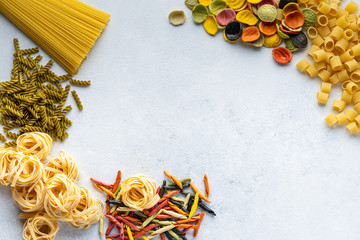 Various types of Italian pasta are on the gray table. Penne, tortellini, fusilli and Farfalle. Copy...