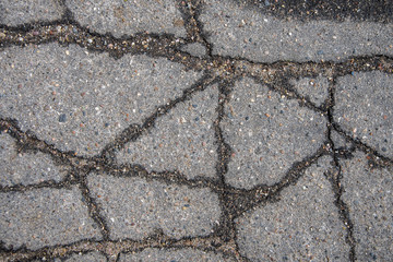 Obraz premium Cracked asphalt in the city, cracks and potholes on the road, textured road surface, selective focus.