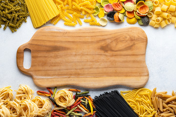 Various types of Italian pasta are on the gray table. Penne, tortellini, fusilli and Farfalle. Copy...