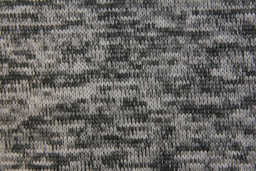 Texture of the knitted fabric. Multi-colored canvas in dark tones. Background with light gray and dark colors.Patterned knitted background.