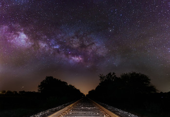 Milky Way core over train tracks. Galactic core rising majestically over abandoned railway tracks in a rural countryside field. - obrazy, fototapety, plakaty