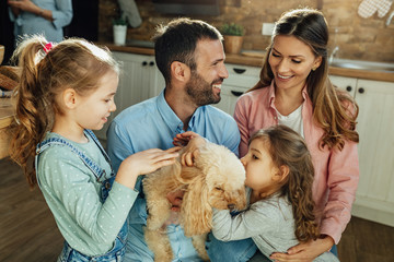 Young happy family enjoying with their dog at home.
