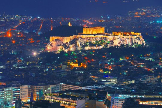 Cityscape of Athens with illuminated Acropolis hill, Pathenon and Herodium construction and sea at night. Athens skyline at night viewed from mount Lykavitos with Acropolis, Greece. Shot in dusk.