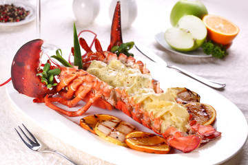 Baked lobster with applesauce and grilled bbq fruit on a white plate in a restaurant.
