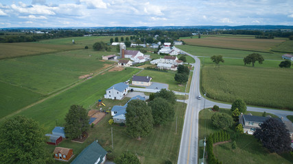 Aerial view of Amish countryside with barns and silos and a one room school house on a sunny summer day