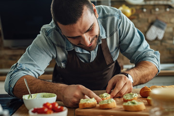Smiling cook making avocado bruschetta in the kitchen.