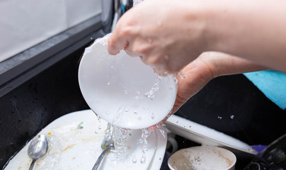 female hands wash dishes in the kitchen sink