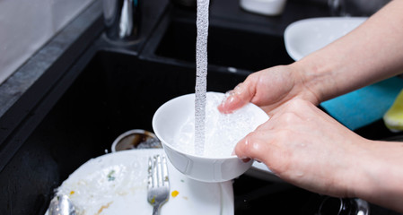 female hands wash dishes in the kitchen sink