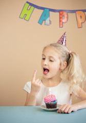  Portrait Caucasian Girl wearing birthday hat tasting a  birthday cake. Happy Birthday Concept.