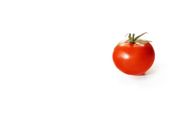 Red tomato stands on a white background. The vegetable is located to the right of the center. Isolated object