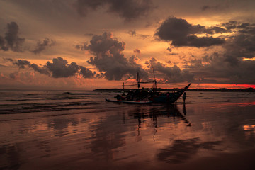 Fototapeta na wymiar Łódź rybacka o zachodzie słońca na tle oceanu i chmur.