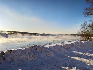White steam over a frozen river and snow drifts on a frosty winter day.Totma.Vologda region.Russia.