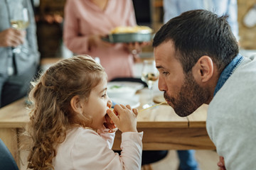Father and daughter sharing a spaghetti while having lunch in dining room.