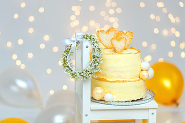 Birthday cake with wreath of flowers, balloons and bright lights bokeh. First birthday. Children's birthday