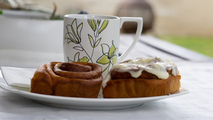 side view of a cup and two cinnamon rolls